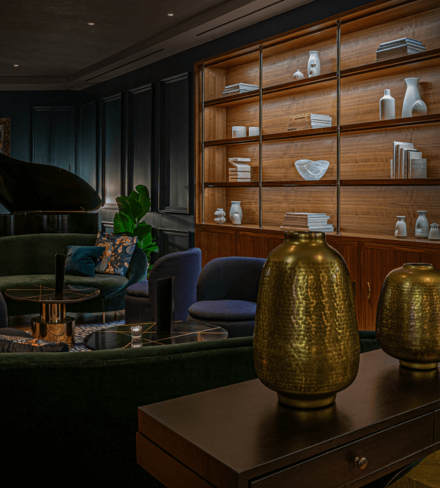 A luxurious lounge with a piano, bookshelves, and decorative vases.