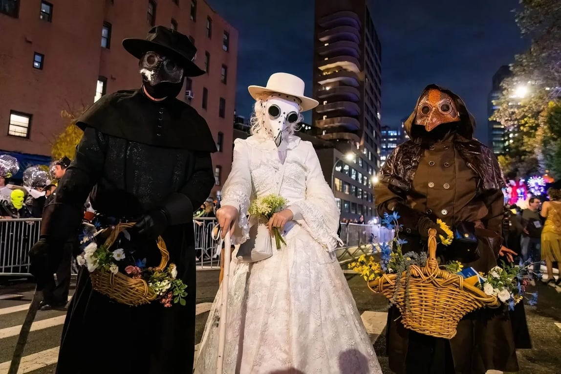 Plague doctor cosplayers carrying flower-filled baskets at the NYC Halloween Parade, part of NYC Halloween parties. Photo by Photo Spirit.