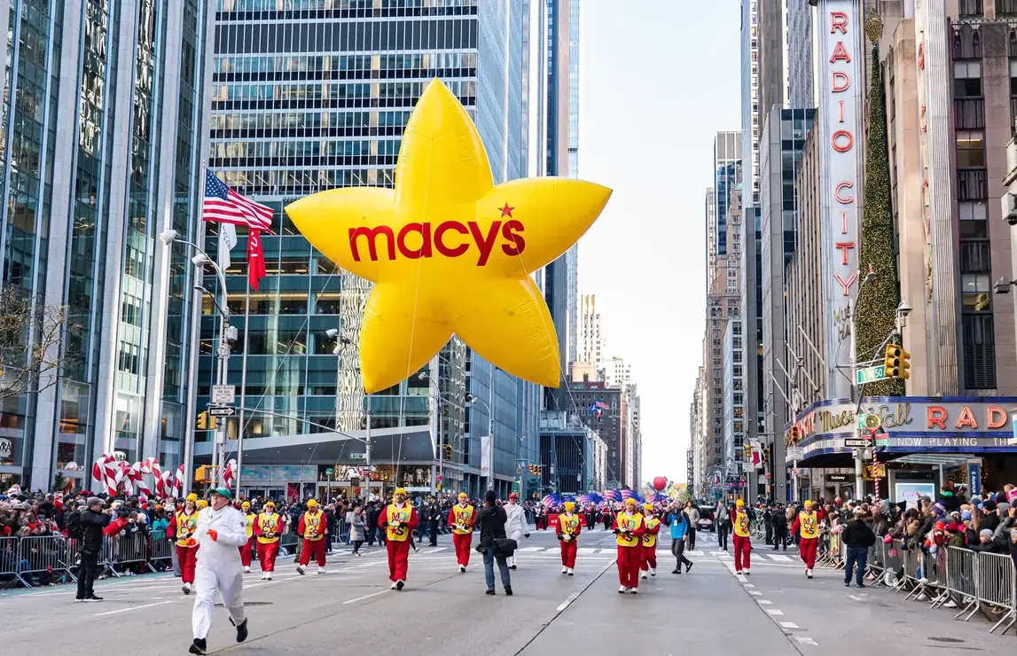 Giant Macy’s star balloon floats above crowds during the Macy’s Thanksgiving Day Parade in the Upper West Side of New York. Photo by Aleksandr Dyskin