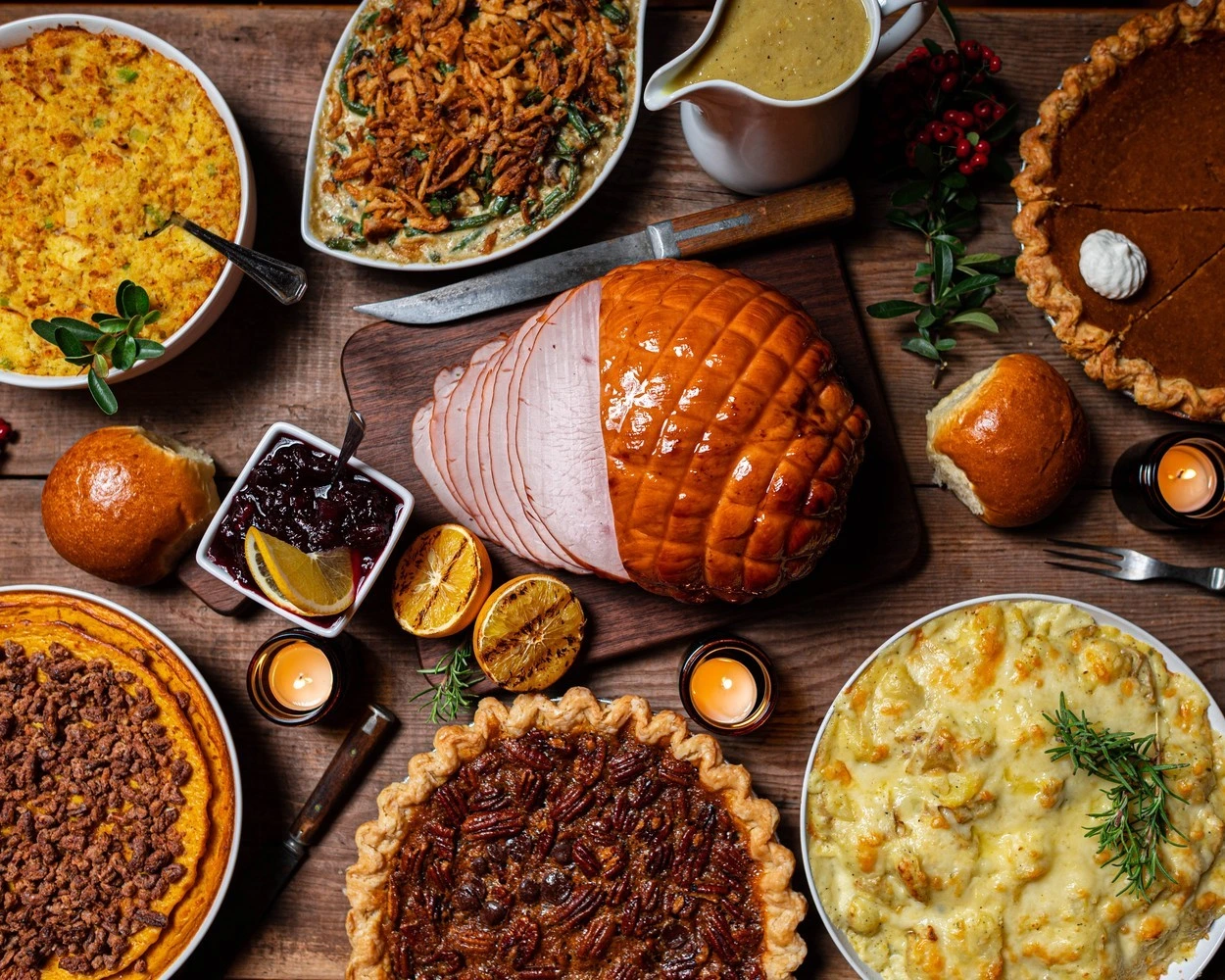A variety of dishes including ham, pies, and sides.